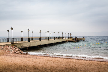 Fototapeta na wymiar Beach, sea and pier in the water on a cloudy summer day