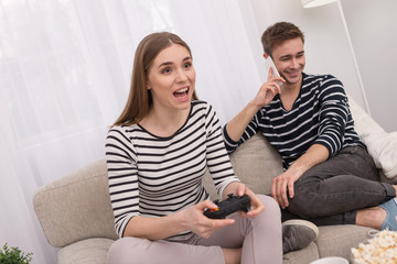 Great game. Inspired concentrated woman playing a game and her boyfriend talking on the phone