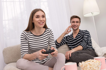 I feel happy. Alert smiling woman playing a game and her boyfriend talking on the phone