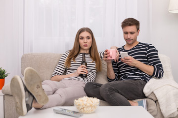 Relaxation. Relaxed happy woman drinking bear and her man using his phone