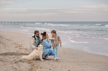 Happy family on a beach. The family walks on a beach with a dog.