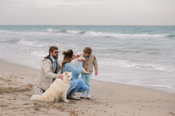 Happy family on a beach. The family walks on a beach with a dog.