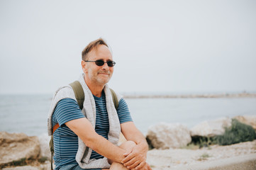 Man enjoying summer vacation by the sea, wearing stripe nautical t-shirt and backpack. Image taken...
