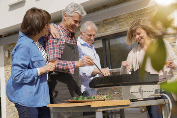 Senior people having fun cooking barbecue grill for lunch