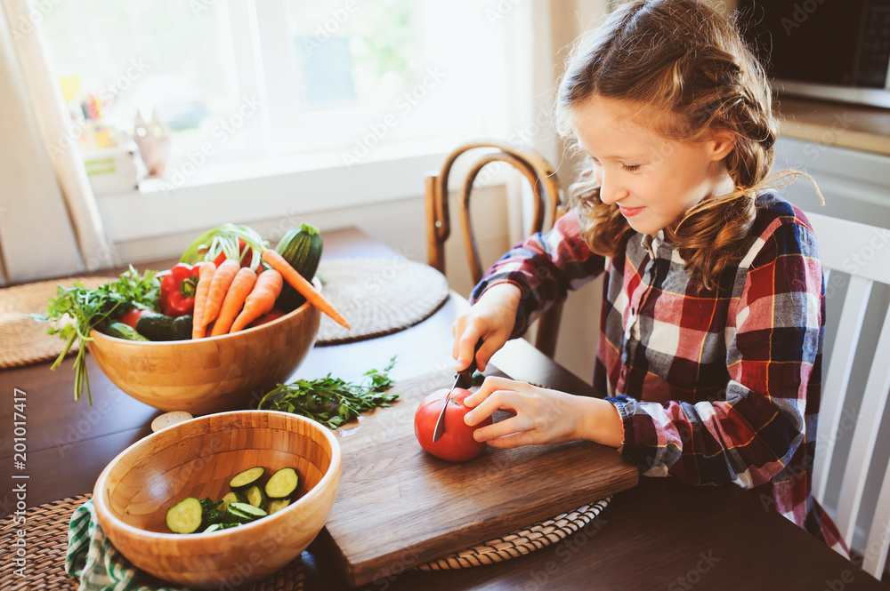 Wall mural child girl helps mom to cook and cut fresh vegetables for salad with knife. Kids learning house work on farm on summer vacations