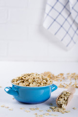 Oat flakes in blue bowl on the kitchen table. Healthy breakfast concept.