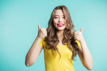 Enthusiastic motivated attractive young woman giving a thumbs up gesture of approval and success