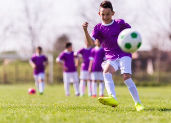 Obraz premium Boy kicking football on the sports field