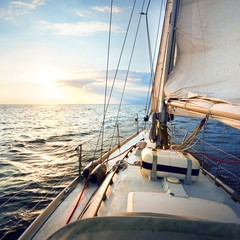 View from the deck to the bow of a sail yacht tilted in a wind on a sunset