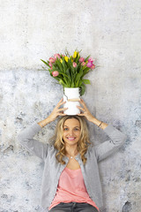 beautiful blond woman with vase full of colorful tulips