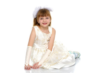 Little girl is sitting on the floor.