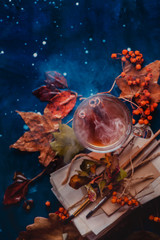 Steaming hot tea in a glass tea cup on a wet wooden background with copy space. Rainy autumn concept with fallen leaves