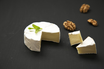 Cheese camembert or brie on dark background. Milk production. Side view. Closeup.