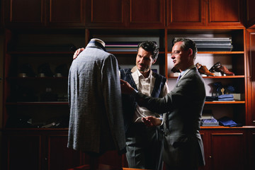 Portarit of a tailor while making a business suit using the tape measure. Concept: Fashion, tailoring, shop