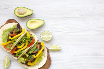 Tacos with pork, fresh vegetables, avocado, lime. White wooden background. Top view, flat, overhead. Copy space.