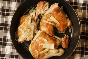Fried chicken with onion in a frying pan.