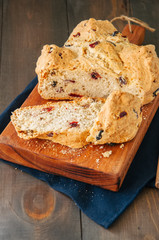 Homemade cranberry raisin and walnut Irish soda bread on a wooden board. Wooden background.