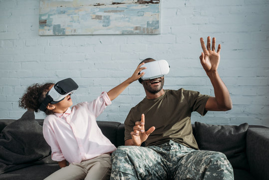 Handsome soldier in camouflage clothes with child playing with virtual reality headsets