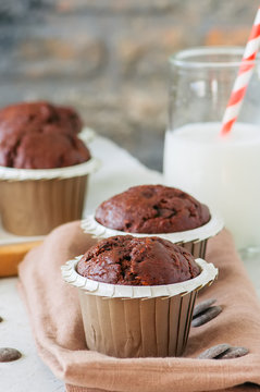 Rich chocolate zucchini muffins with chocolate chips. Close up. White stone background.