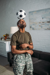 African american soldier playing with football ball on head