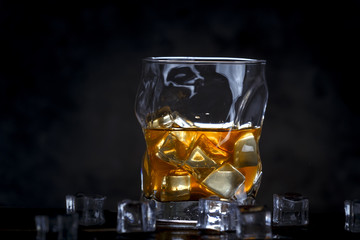 Alcohol in glass with ice on dark background