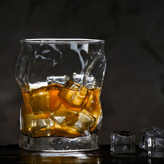 Alcohol in glass with ice on dark background