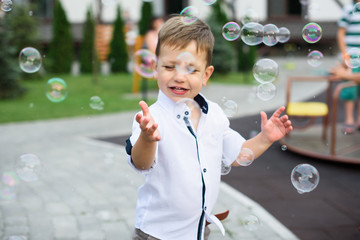 Cute male child catches soap bubbles