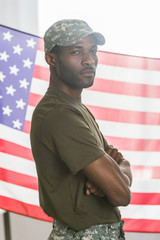 Confident african american man in camouflage clothes in front of us flag