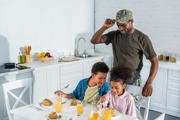 Army soldier father looking at happy kids enjoying meal in kitchen © LIGHTFIELD STUDIOS