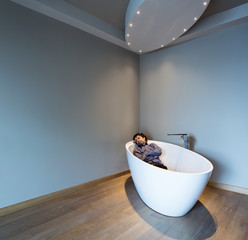 Man inside a luxury bathtub in modern apartment. Man sleeps clothed in a modern bathing helmet.