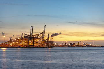 Sunset and gradient blue sky on the cranes of the biggest European seaport, Rotterdam, Netherlands