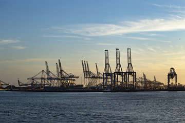 Fototapeta na wymiar Sunset and gradient blue sky on the cranes of the biggest European seaport, Rotterdam, Netherlands