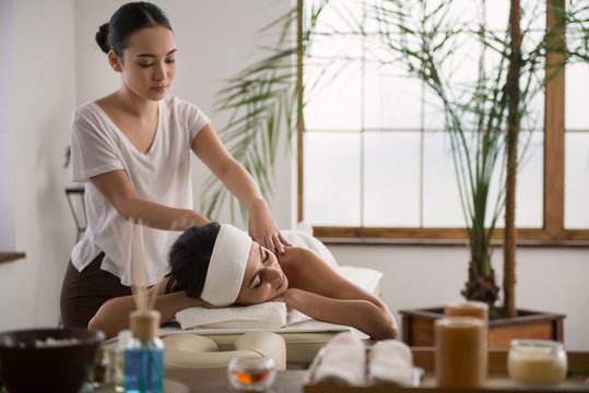 Peaceful atmosphere. Delighted young woman smiling while relaxing during the massage procedure
