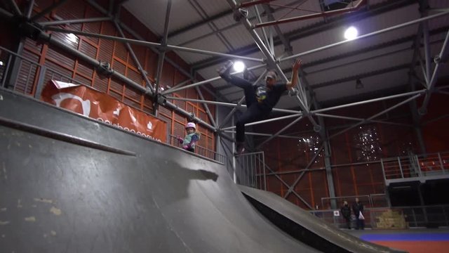 A man on roller skates trying to make jumps on the ramp and falls, slow motion
