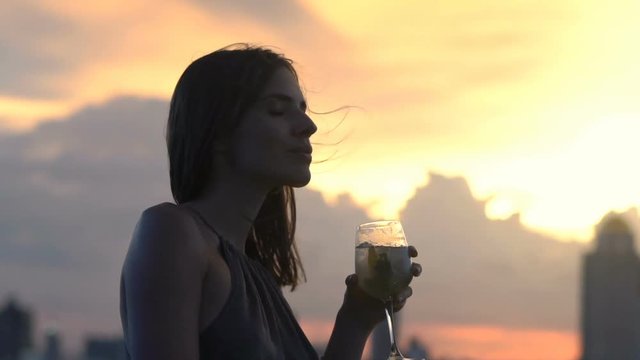 Young woman admire sunset and drinking cocktail is skybar, super slow motion 120fps
