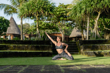 woman practicing yoga with beautiful green plants on background, Bali, Indonesia
