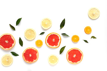 Pattern of fresh fruits on a white background, top view, flat lay.   Composition of green leaves and slices of citrus fruits: grapefruit, lemon, mandarin. Healthy food background, wallpaper, collage.