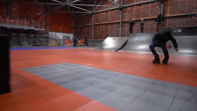 A man in a skate park performs grab at 180, slow motion