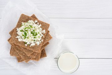 top view of glass of milk and crackers with cottage cheese on wooden table