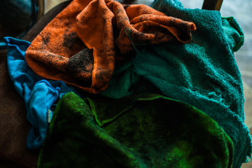 Pile of colorful dirty rags laying nearby chopper on the wooden chair. Old garage