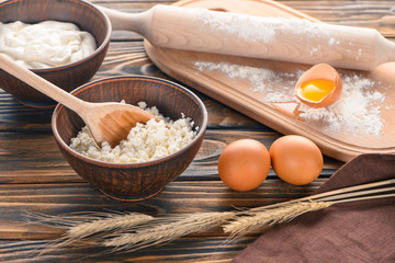 fresh cottage cheese, wheat ears, sour cream, eggs and flour on wooden table