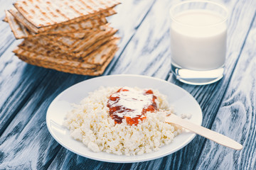 close-up view of cottage cheese with jam in plate, glass if milk and crackers on wooden table