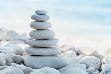 Stack of white pebbles stone against sea background for spa, balance, meditation and zen theme.