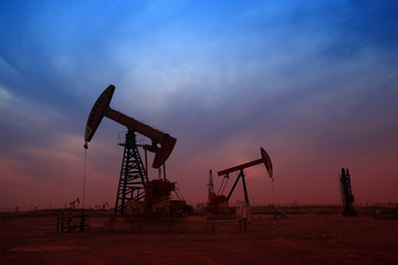 Fototapeta premium Pumping unit in the work, under the background of the setting sun