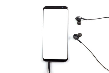 Technology concept, hand holding or torch smartphone and using a new modern smartphone with white screen and black headphone cable, isolated on white background with clipping path top view.