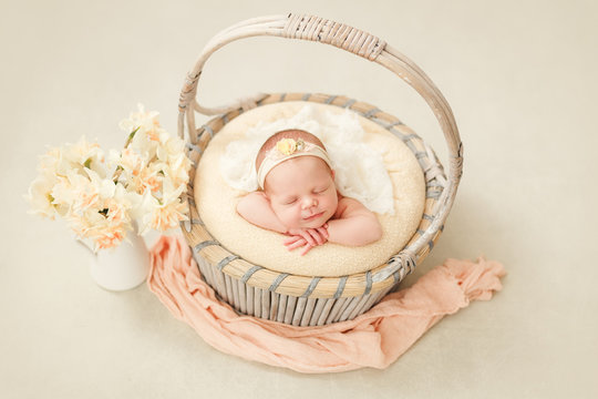 Photoshoot of a sleeping newborn girl in a basket with a bandage on her head, a gentle image of spring, a jar with daffodils