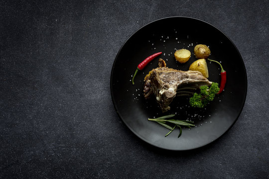 From Above a roast lamb on rectangular black plate