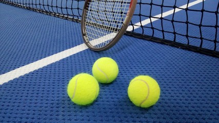 Tennisschläger mit Tennisbällen auf einem Indoor Tennisplatz