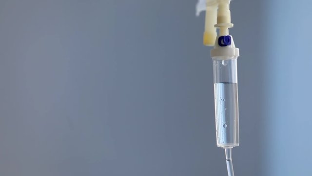close up of a slow intravenous drip with a blurred blue background