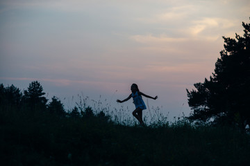 Little cutie girl in a white dress dancing in the sunset